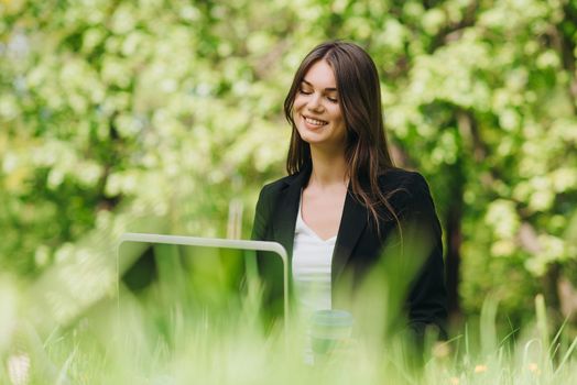 Beautiful business woman in suit using laptop computer in the park