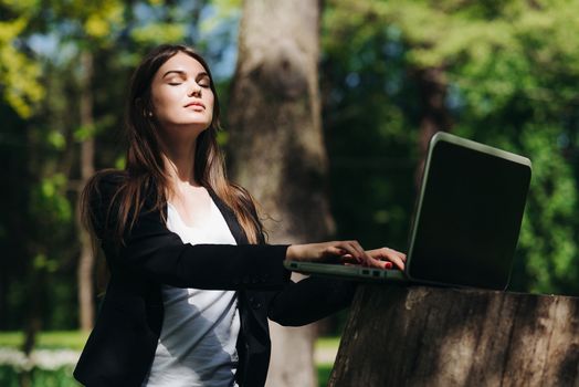 Beautiful business woman in suit using laptop computer in the park