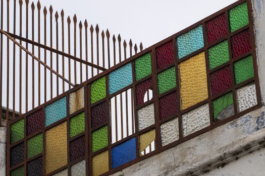 Close up view of a rusty old colorful glass balcony.