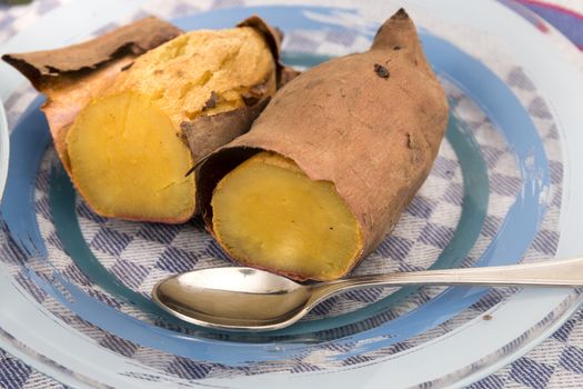 Cooked oven sweet potatoes on a dish with spoon.