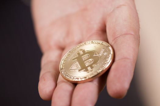 male hand holding a bitcoin, a digital crypto currency.