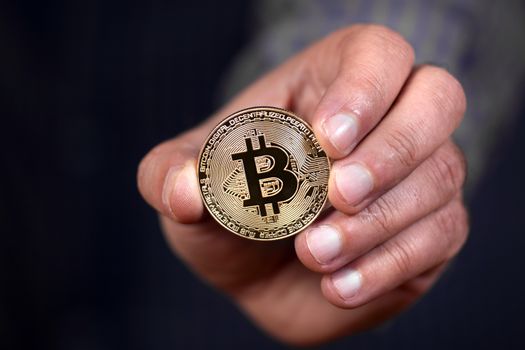 male hand holding a bitcoin, a digital crypto currency.