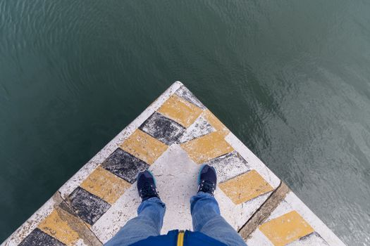 man legs on corner of docks, top view to the water.