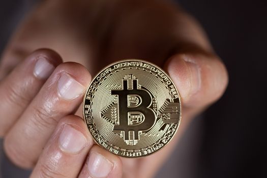 male hand holding a bitcoin, a digital crypto currency.