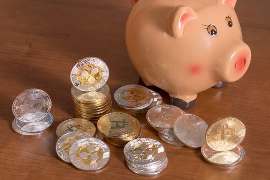 Piggy bank with several crypto currency coins on top of wooden table.