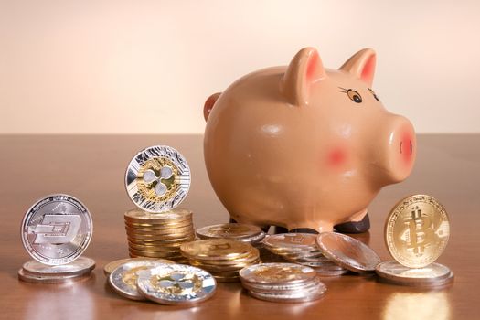 Piggy bank with several crypto currency coins on top of wooden table.