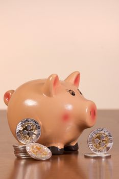 Piggy bank with several ripple coins on top of wooden table.