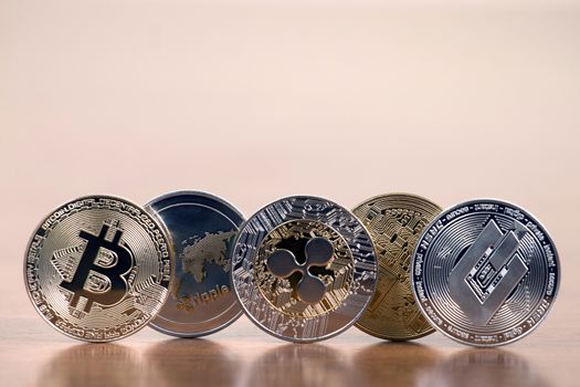 several aligned crypto currency coins on top of wooden table.