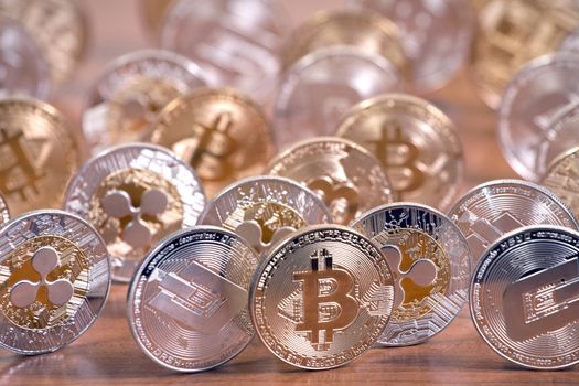 several aligned crypto currency coins on top of wooden table.