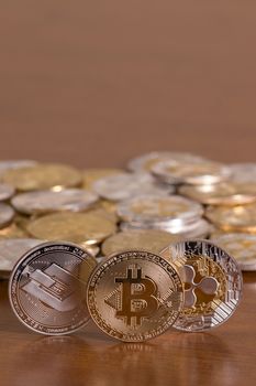 several aligned crypto currency coins on top of wooden table.