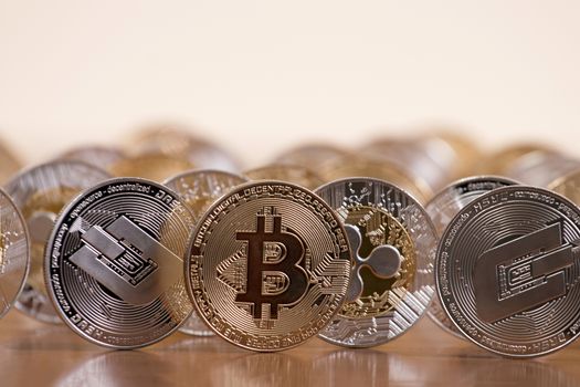 several aligned crypto currency coins on top of wooden table.