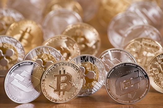 several aligned crypto currency coins on top of wooden table.