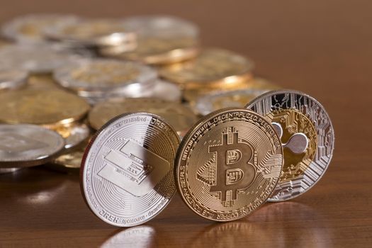 several aligned crypto currency coins on top of wooden table.