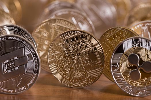 several aligned crypto currency coins on top of wooden table.