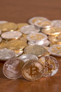 several aligned crypto currency coins on top of wooden table.