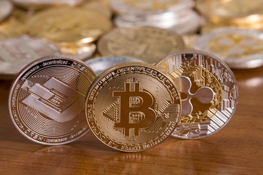 several aligned crypto currency coins on top of wooden table.