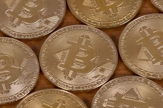 several golden bitcoins on top of wooden table.