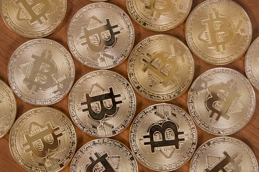 several golden bitcoins on top of wooden table.