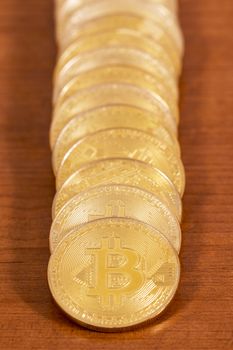 several golden bitcoins stacked on top of wooden table.