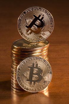 several golden bitcoins stacked on top of wooden table.