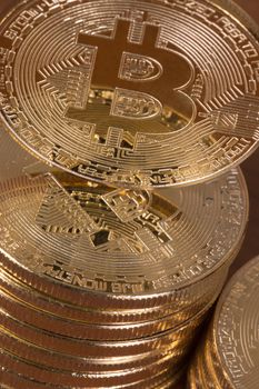 several golden bitcoins stacked on top of wooden table.