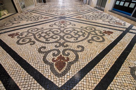 Street of Santo Antonio in Faro city that includes many stores, and beautiful cobblestone artwork.