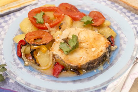 Traditional portuguese meal of fish with potatoes and tomato, made on the oven.