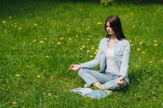 Beautiful young girl in casual clothes meditating in spring park