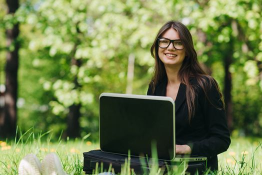 Beautiful business woman in suit using laptop computer in the park