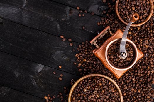 Coffee background, top view with copy space. Ground coffee, coffee mill, bowl of roasted coffee beans on dark wooden background
