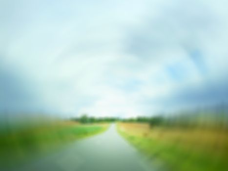 Defocused image of a country road in field, on a rainy day. Radial blur effect.