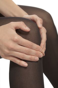 Close-up of female legs with pantyhose. Woman is rubbing her knee to relax pain.