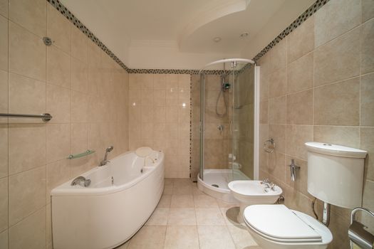 spacious beige tile bathroom with bath tube sink and toilet