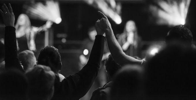 black and white of happy couple in love holding hands during worship and music live event with musicians on stage