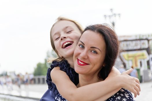 Embracing and laugh mother and daughter in summer time