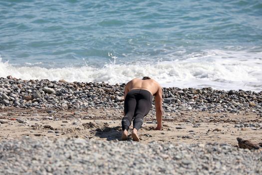 Shot Of Attractive Man Doing Push Ups On The Beach