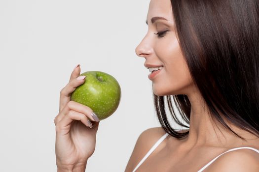 Attractive smiling woman portrait on white background with apple.