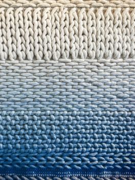 White and blue winter knitted background with simple ornament. Handcrafted material.