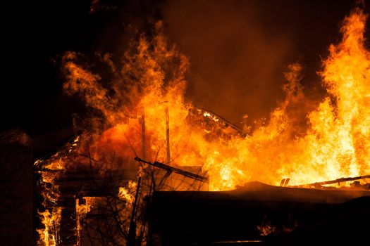 Arson or nature disaster - burning fire flame on wooden house roof