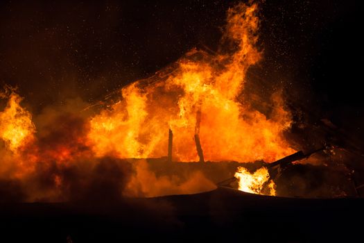 Arson or nature disaster - burning fire flame on wooden house roof