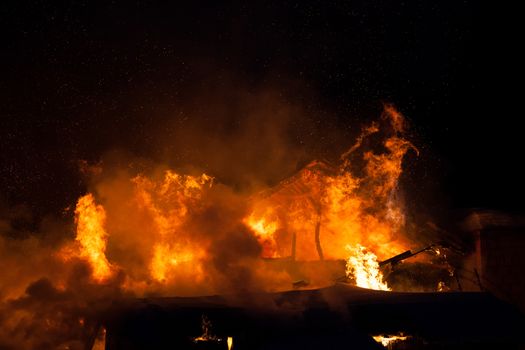 Arson or nature disaster - burning fire flame on wooden house roof