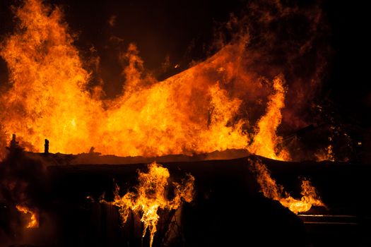 Arson or nature disaster - burning fire flame on wooden house roof