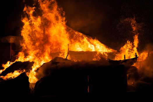 Arson or nature disaster - burning fire flame on wooden house roof