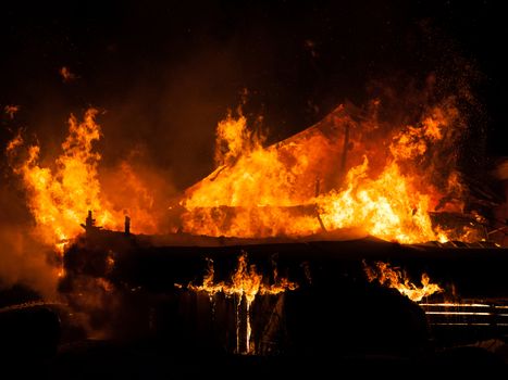 Arson or nature disaster - burning fire flame on wooden house roof