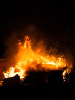 Arson or nature disaster - burning fire flame on wooden house roof