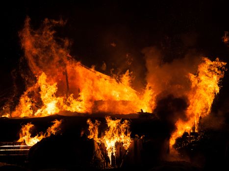 Arson or nature disaster - burning fire flame on wooden house roof