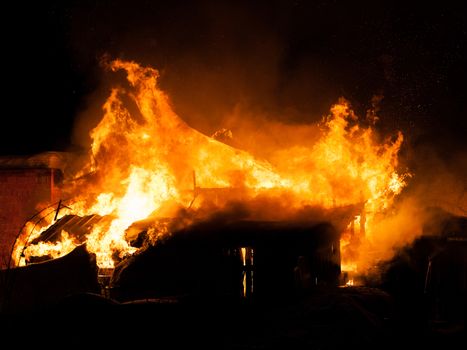 Arson or nature disaster - burning fire flame on wooden house roof