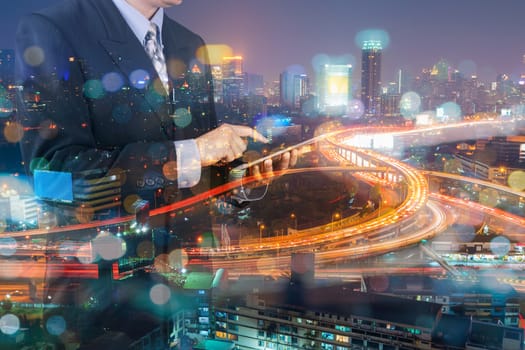 Double Exposure of Businessman Hold Digital Tablet and Modern Capital City of Bangkok at Twilight with Expressway or Superhighway as Smart City Lifestyle concept
