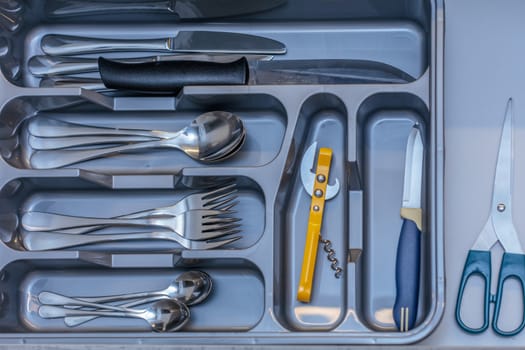 Grey silverware drawer with forks spoons and other  kitchenware
