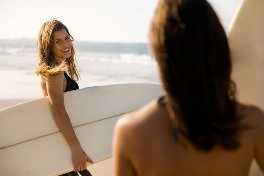 Two beautiful surfer girls at the beach ready for surfing